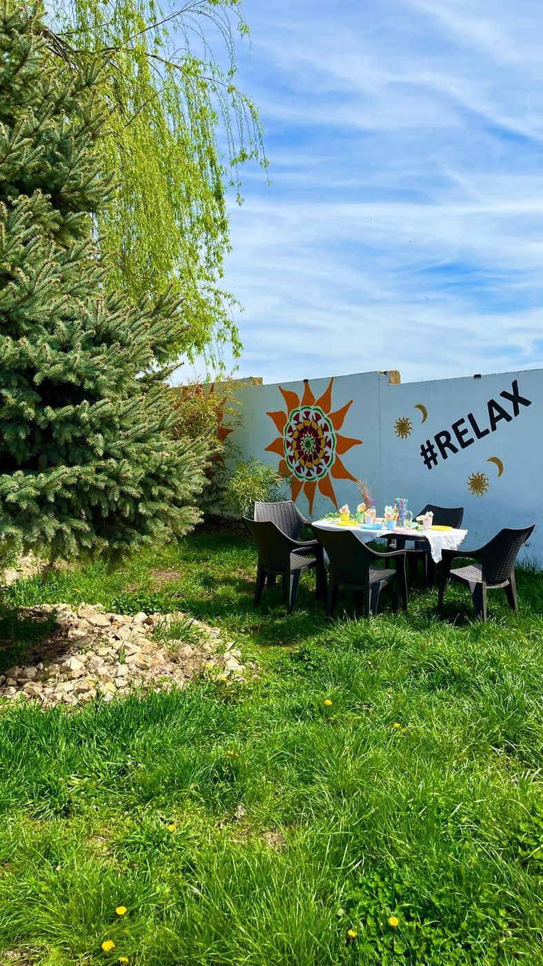 Masă pregătită în grădină, lângă peretele pictat cu mesajul #RELAX