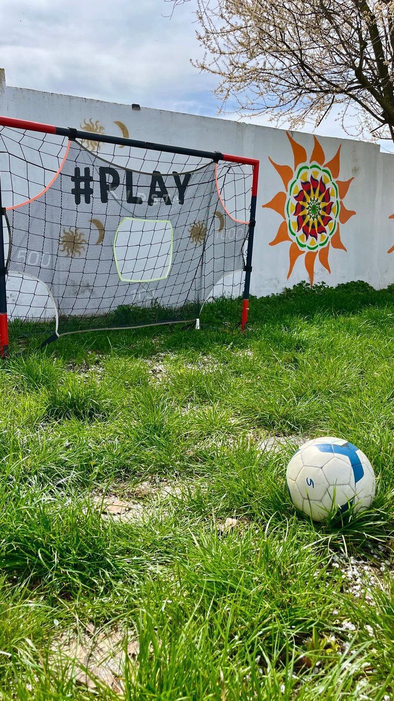 Poartă de fotbal cu mesajul #PLAY și o minge pe iarbă